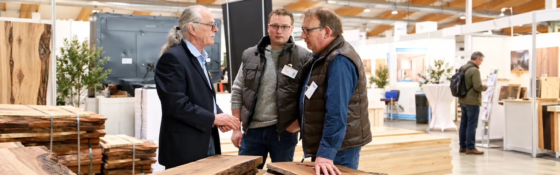 Fachbesucher im Gespräch an einem Messestand auf der HolzTek